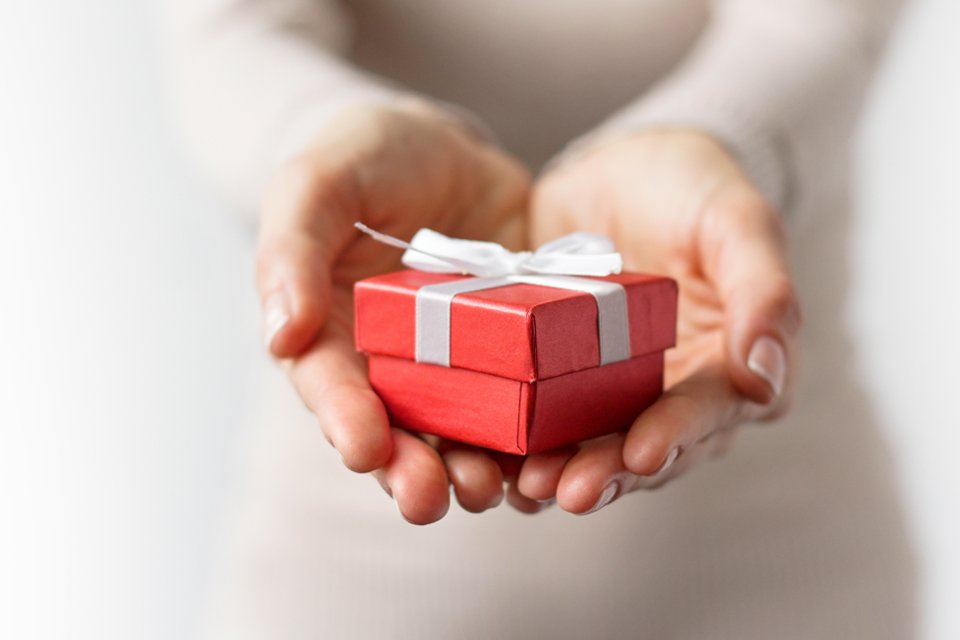 A womans hands hold a small red gift box.
